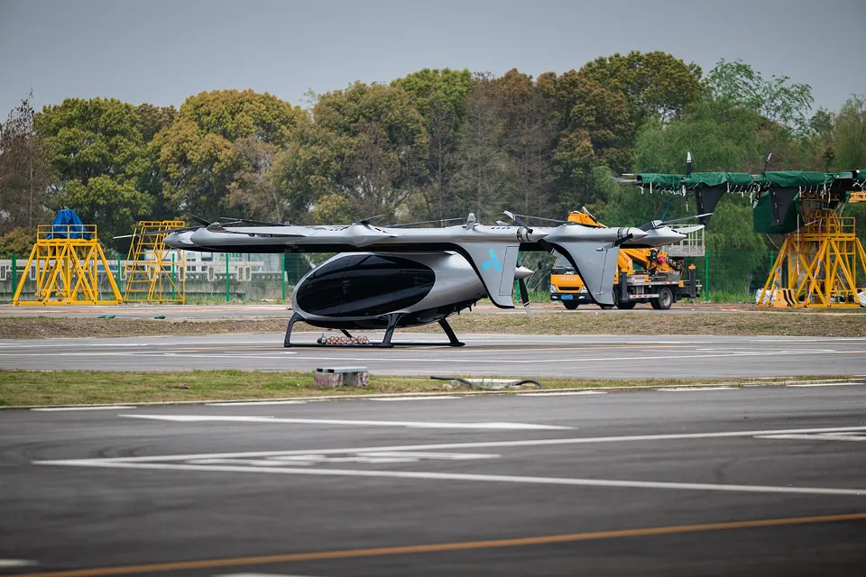 Silver AutoFlight CarryAll eVTOL with a long front wing, rear wing and propellers on booms, parked on a test-site apron